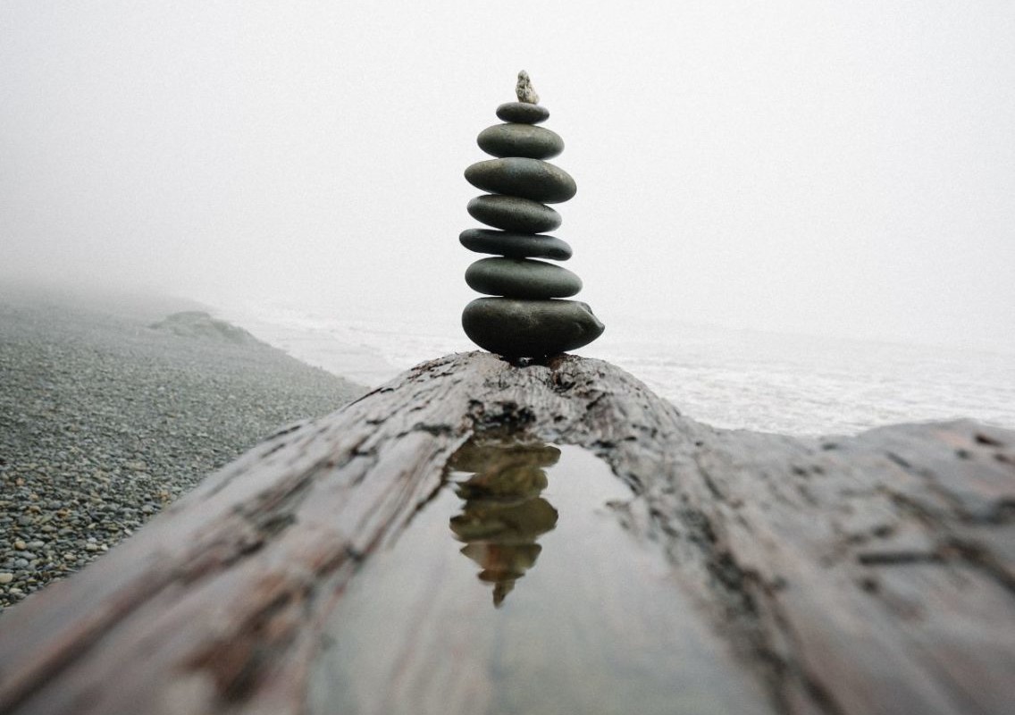 Stones stacked in balance ontop of a tree trunk.