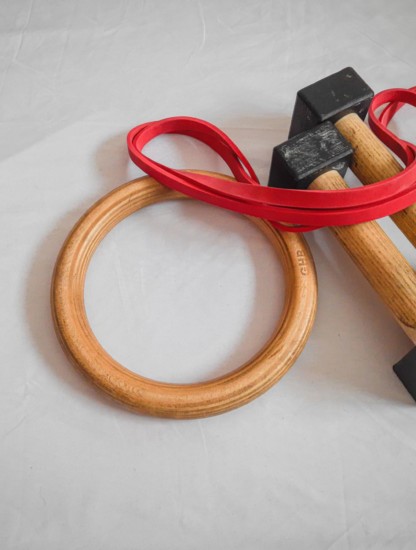 This image shows some gymnastic rings, a set of parallettes, and a resistance band positioned on a white background,