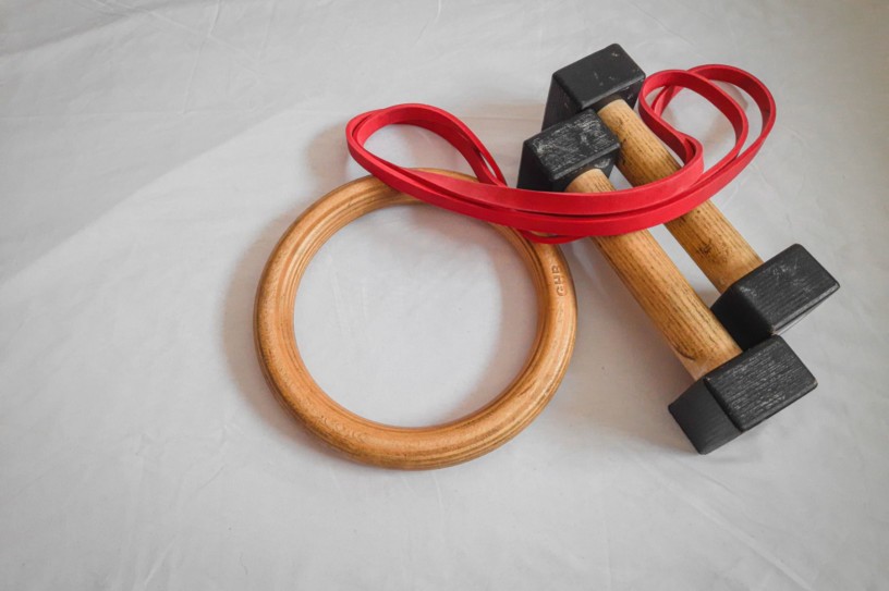 This image shows some gymnastic rings, a set of parallettes, and a resistance band positioned on a white background,